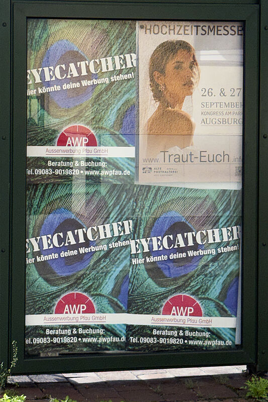 Beleuchtete City-Light-Vitrine mit AWP-Plakaten an einer Augsburger Haltestelle